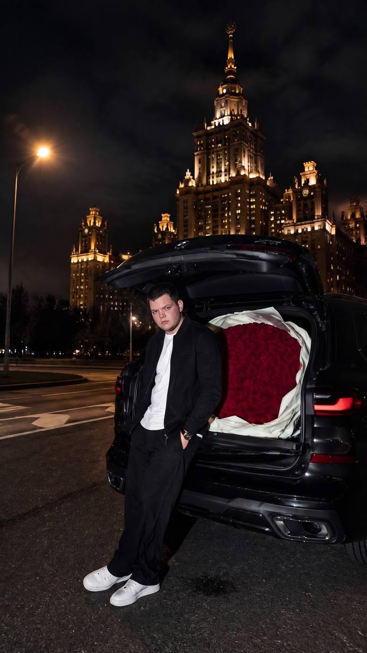 Исходная фотография: артист рядом с чёрным автомобилем и букетом алых роз на фоне ночного города